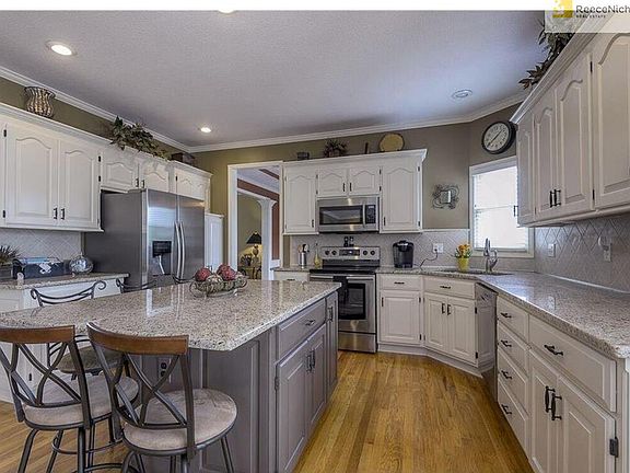 The stunning Kitchen boasts beautiful granite counters, tile backsplash, hardwood floors, and stainless steel appliances.