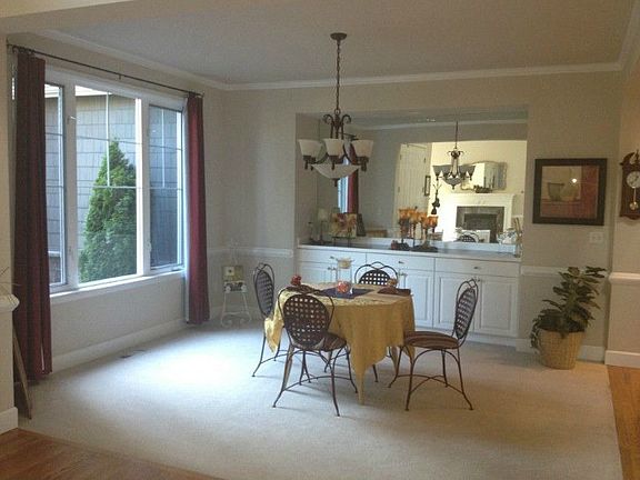 Sunny spacious entry with wrought iron chandelier, hardwood floors, and large picture window. Notice the chair rail trim and extra tall baseboards.