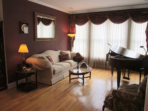 Grand piano sized room with pillars, hardwood flooring and crown molding details.