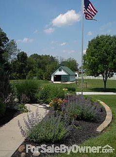 View of barn and fenced in pasture from front sidewalk and flower bed.