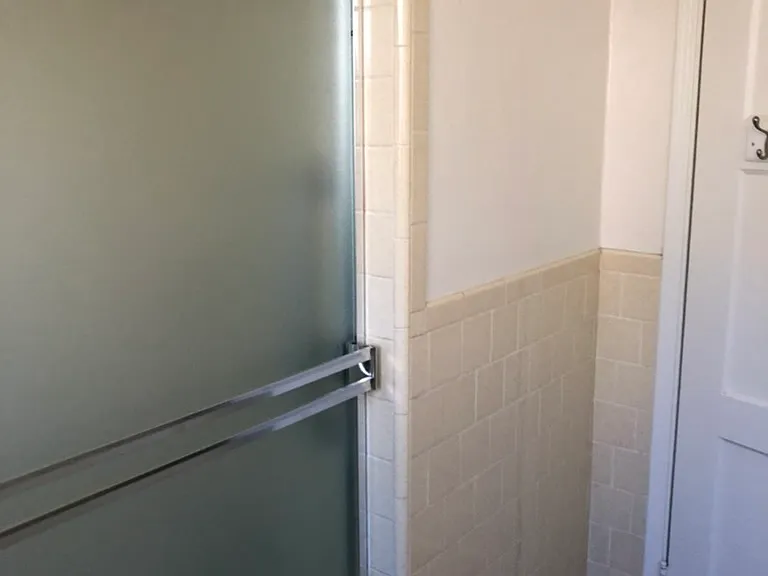 Shower tub combo with safety bars and glass enclosure. Wall mount and handheld shower head.