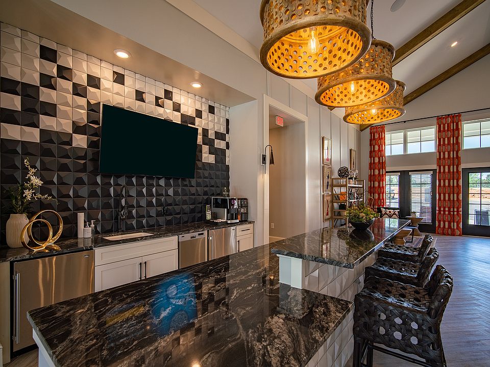 Clubhouse with open-concept kitchen with sleek marble countertops, modern geometric backsplash, and elegant pendant lighting.