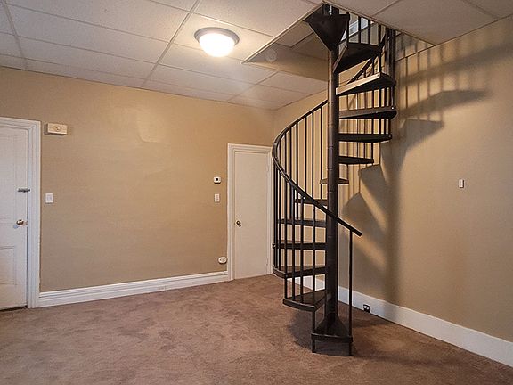 Living room with view of spiral staircase to 2nd floor. View from kitchen entrance.
