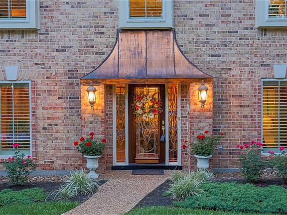 Beautiful entry with copper hood, leaded glass front door and side lights. Notice the plantation shu
