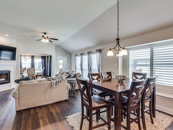Expansive living area featuring wood-finish flooring, a white mantel fireplace, and a ceiling fan
