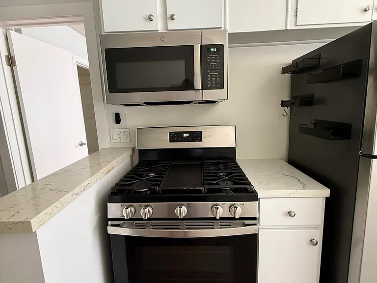 Stove, microwave kitchen cabinets entryway to the bedroom.