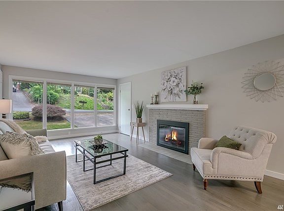Charming living room with wall of windows, wood burning fireplace, refinished hardwood floors with a touch of gray, new trim and new paint.