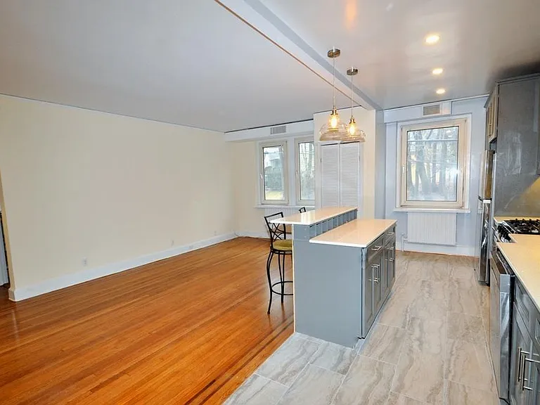 Renovated Kitchen with center Island, pendent lighting, Granite Counters, Stainless Steel Appliance including a dishwasher, range, microwave and refrigerator. The wall separating the eat-in-kitchen and living room have been removed and a center Island ins