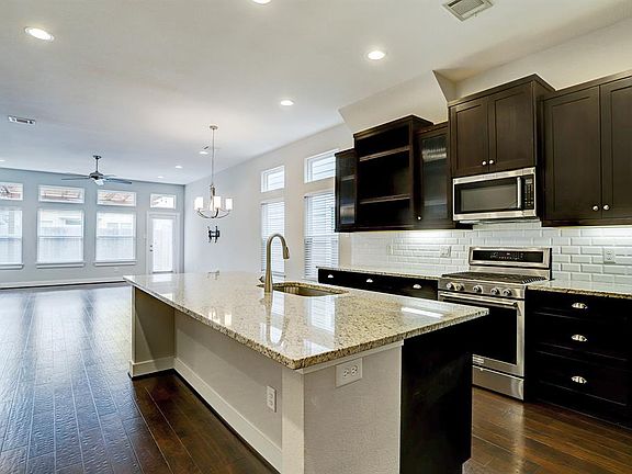 Stunning kitchen has it all with custom espresso cabinetry (including open shelving and glass-fronts), granite counters, subway tile backsplash with under cabinet lighting, a built-in wine chiller, and stainless steel appliances.