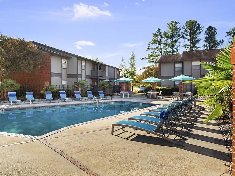 Unwind poolside with shaded seating and sun loungers at Lakeland East Apartments in Flowood, MS. Managed by Highlands Vista Group.