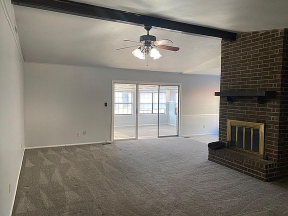 Living room with wood burning fireplace. Sliding glass doors into sunroom.
