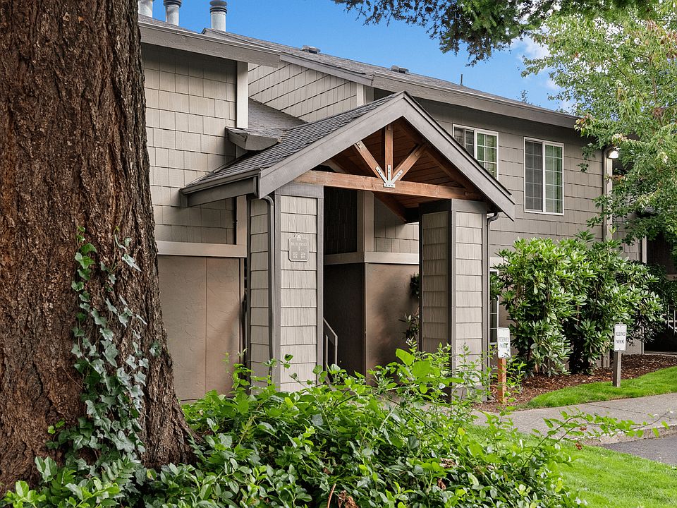 Charming apartment building entrance surrounded by lush landscaping.