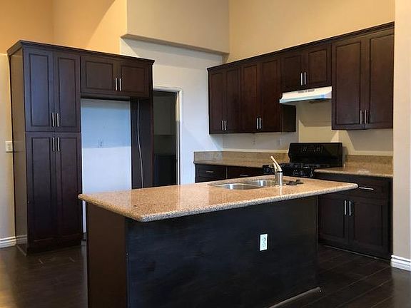 Kitchen island with sink and dishwasher. Laundry room is beyond towards garage entry.