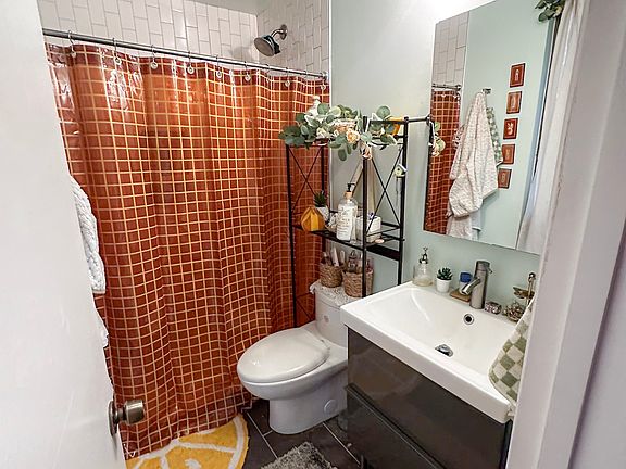 Primary bedroom's en-suite bathroom with slate floor, tiled shower, floating vanity, and medicine cabinet