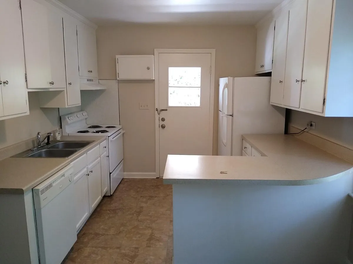 Eat-in kitchen with recently added appliances and door adjacent to carport. (Photo taken from dining area) - 1204 Wellford St