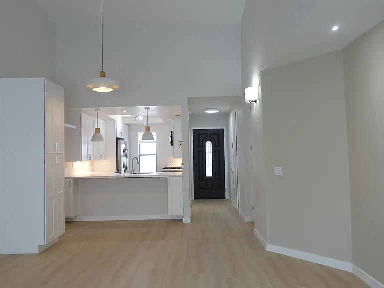 Open floor plan: Vaulted ceiling with white and oak chandelier. Oak floors throughout home