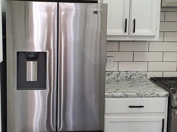 Part of one side of the kitchen with brand new refrigerator.