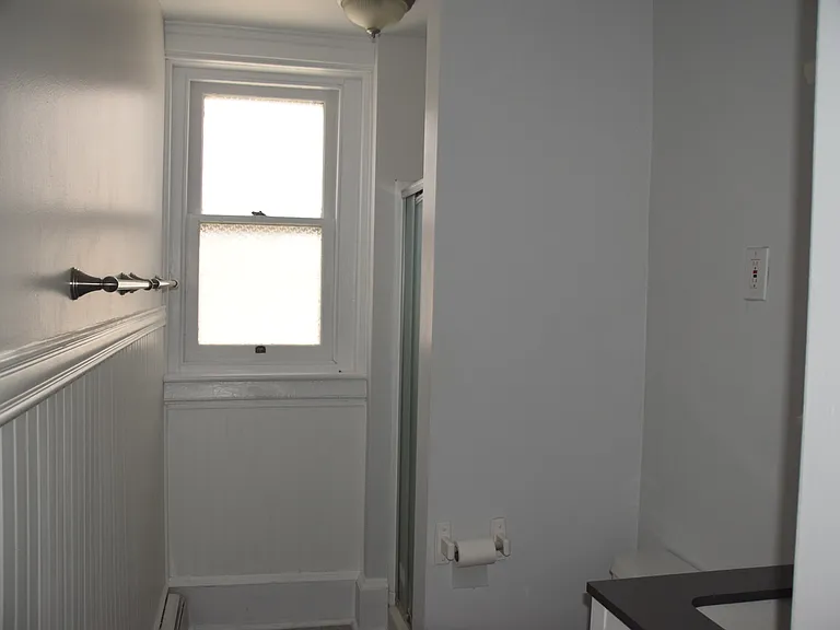 Remodeled bathroom, wainscoting, stand-up shower, separate vanity light, window.