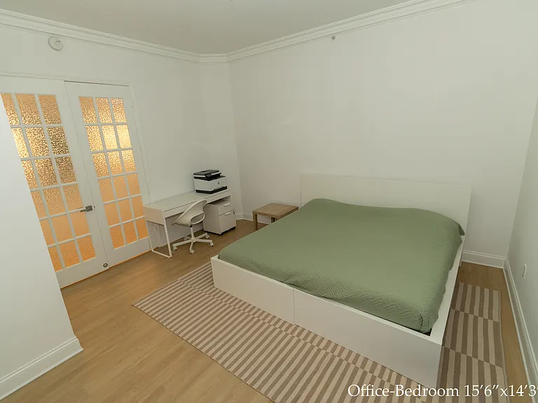 An office-bedroom with a desk and a printer.