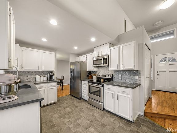 Stainless appliances, white cabinetry & recessed lighting. 