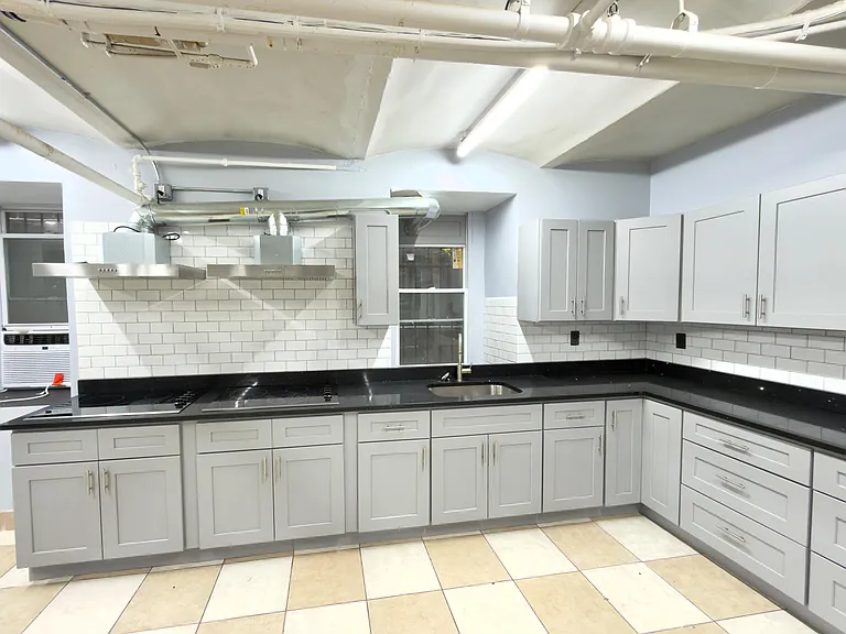 Spacious U-shaped kitchen with ample shaker cabinetry, subway-tile backsplash, long counters, and a stainless sink.