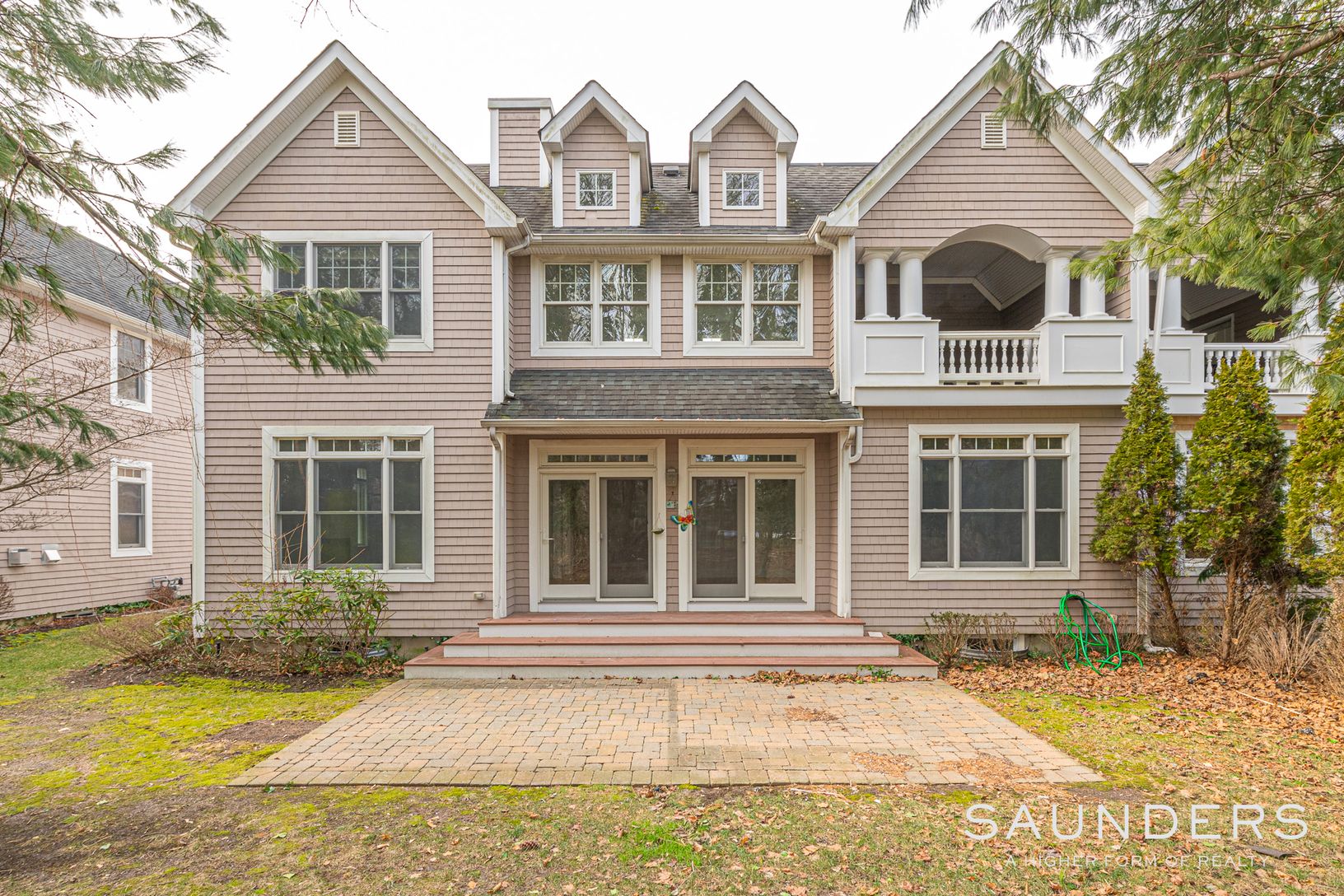 Symmetrical back view of home with lots of windows and doors leading to outdoor paved patio