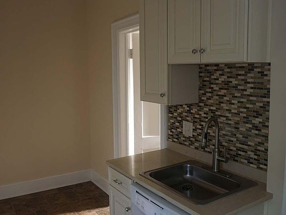 New kitchen with dishwasher under sink and tile backsplash