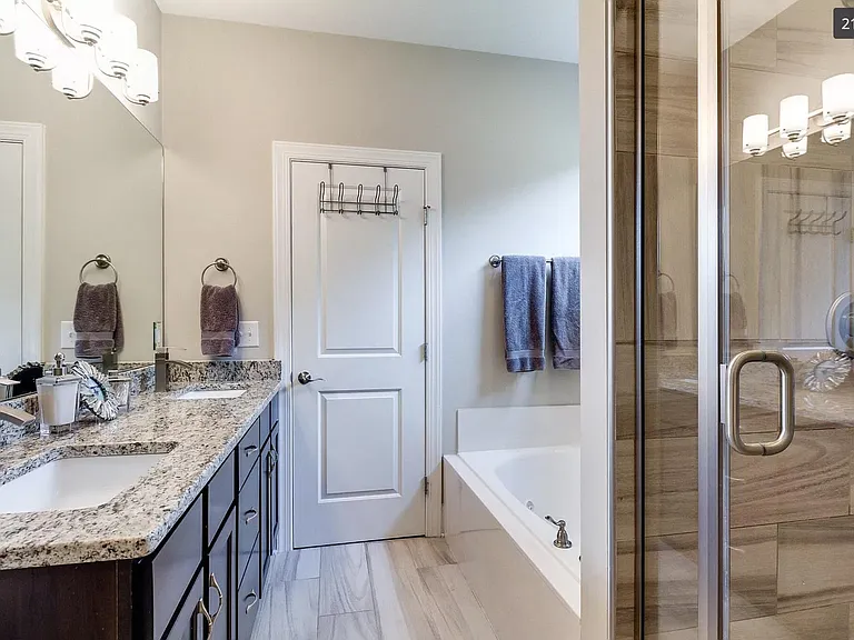Full en suite master bathroom featuring double basins, shower and tub