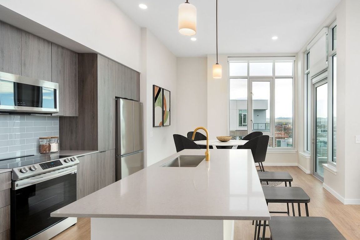 Signature Collection Kitchen with dark cabinetry, marbled quartz countertops and backsplash, upgraded stainless steel appliances, pendant lighting.