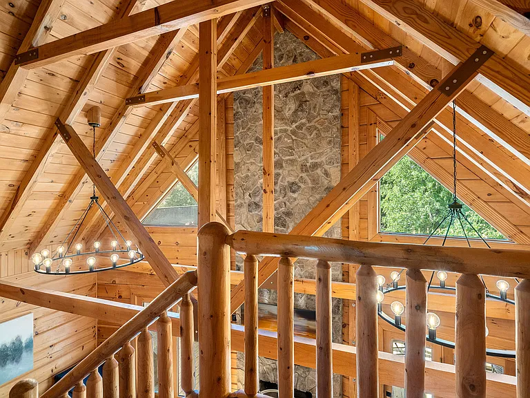 2 story family room - this is the view from the upstairs bedroom overlooking the family room. Floor to ceiling stone fireplace, pine clad ceilings and walls, modern wagon wheel chandeliers and exposed beams make this home standout.