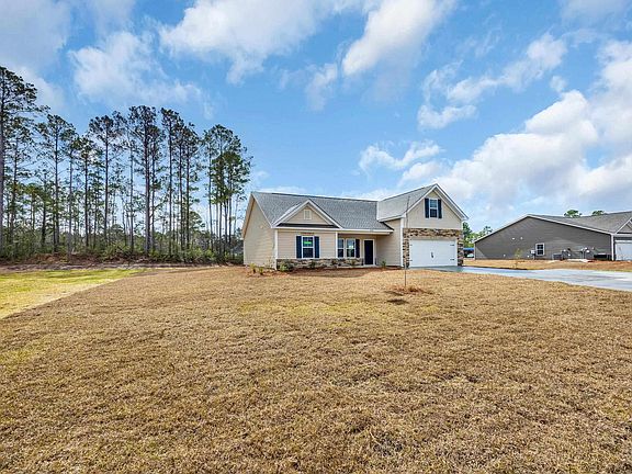 View of front of property featuring a front lawn, stone siding, and driveway