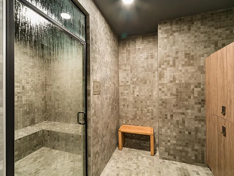 A calming steam room with tiled walls and warm finishes, creating a quiet space to decompress and recharge after the day.