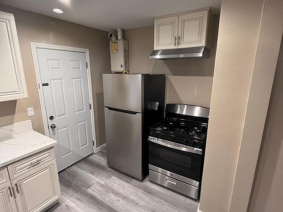 Kitchen with refrigerator, stove, rangehood and tankless