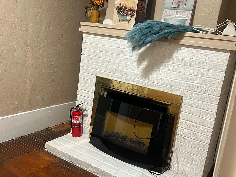 Decorative fireplace with a painted brick surround and mantel ledge, adding character to the common living area.