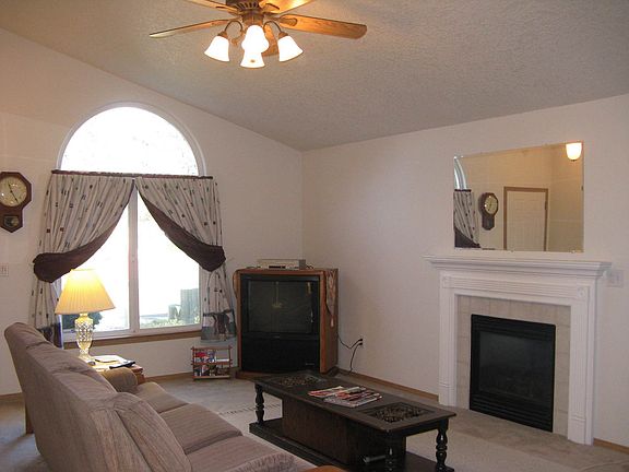 Living room has vault, fireplace and ceiling fan.
