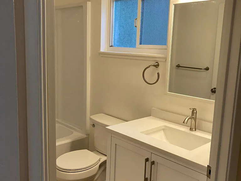 Bathroom with shower over tub. Sink with storage.