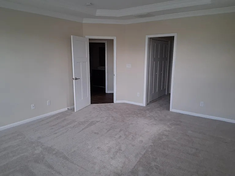 Large primary bedroom with wall to wall carpeting.