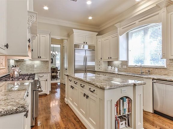 A chef's kitchen with 6 burner gas range, stainless steel appliances, ample storage and large granite slab for prep.