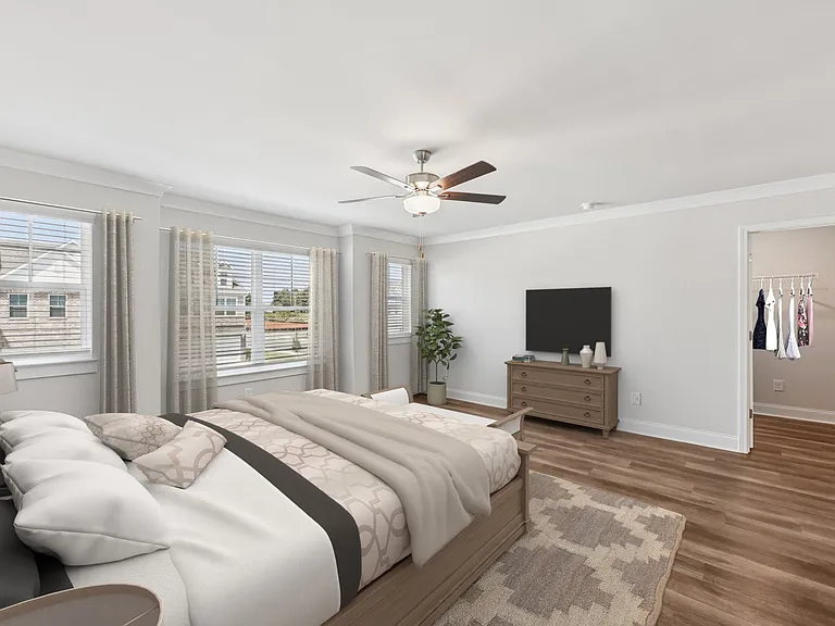 Another view of the spacious primary suite showcasing a grand bed and modern ceiling fan.