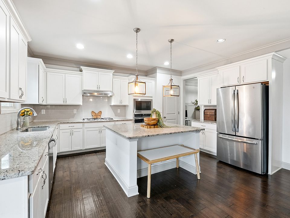 Spacious, light-filled kitchen with white cabinetry, granite countertops, stainless steel appliances, large island, and ample storage_perfect for gatherings and daily meals.