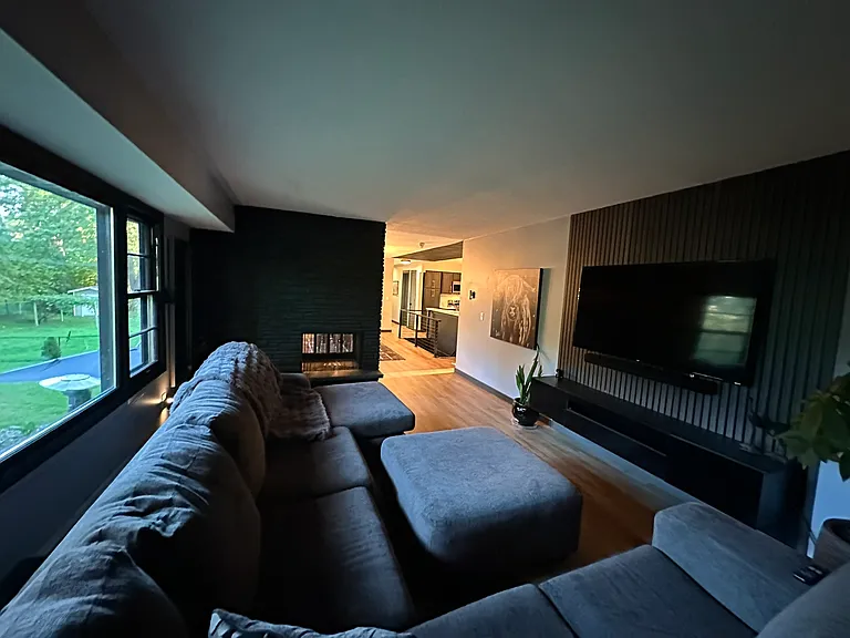 Expansive living room with textured panels and a floating entertainment center continue modern theme throughout the home.