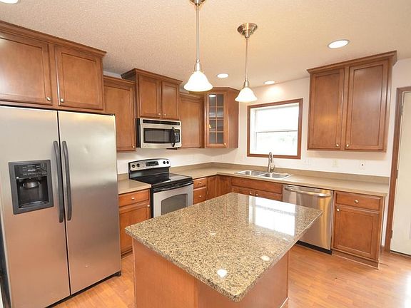 Well-appointed kitchen with stainless steel appliances, center island, ample cabinetry, and pendant lighting. Open layout flows seamlessly into dining and living spaces.