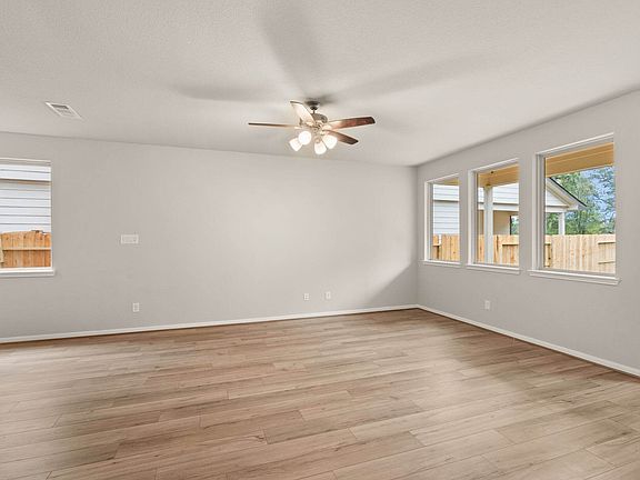 An additional view of the family room featuring gorgeous floors, ceiling fan with lights and large w