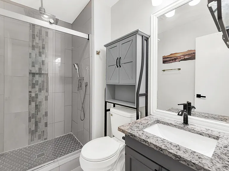 Updated primary bathroom with granite countertop and custom shower.