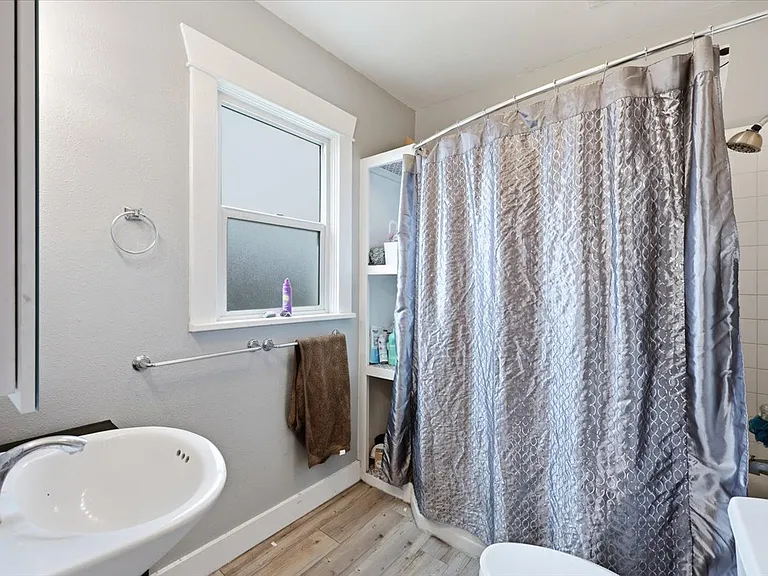 The bathroom is well fitted with lots of storage, a curved shower curtain over the tub/shower combo, and fresh, calming paint.