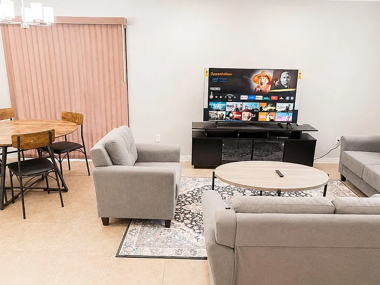 Open-concept living area with lounge seating, TV console, and an adjacent dining table near the sliding patio door.