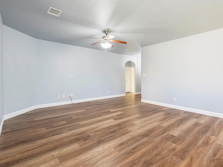 Spare room featuring arched walkways, wood finished floors, and ceiling fan