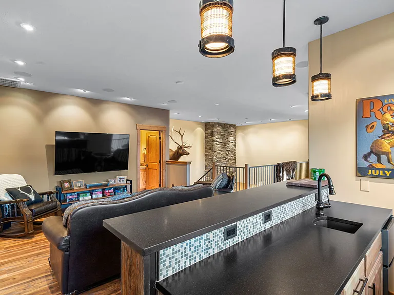 Wet bar with fridge, leathered granite countertop and more custom lighting.