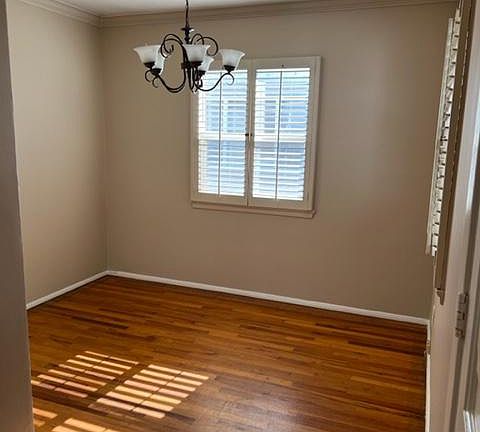 Dining room with chandelier and plantation-style shutters and hardwood floors.