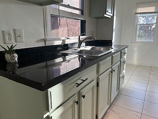 Spacious kitchen with many cabinets and windows. Granite countertops.